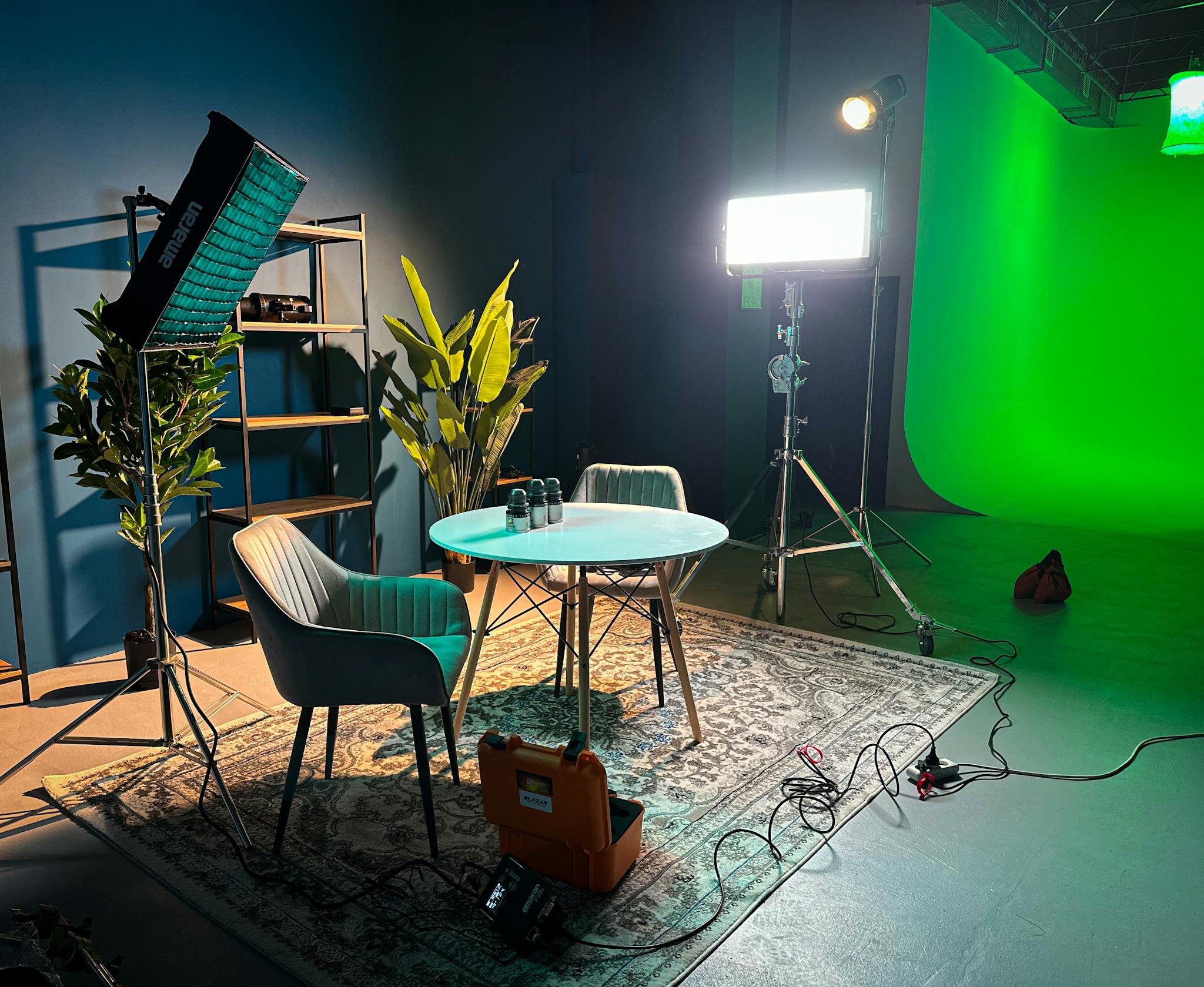 A modern, well-lit indoor studio setup designed for filming, featuring green screen and stylish decor.
